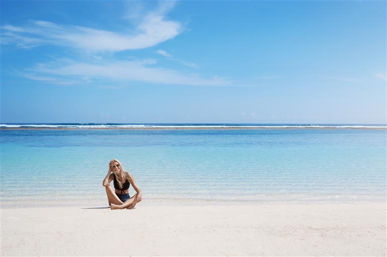 mulher sentada na areia sorrindo
